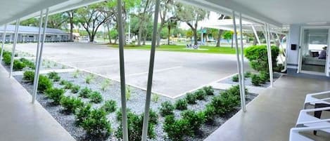 A covered outdoor area with a view of a parking lot and trees.