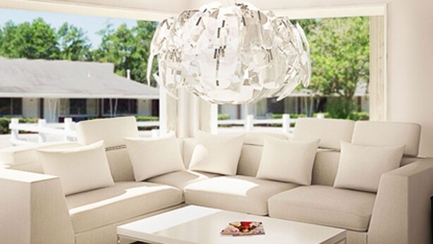 A modern living room with a sectional sofa, a coffee table, and a unique spherical chandelier. - Sun Plaza Motel (Silver Springs)