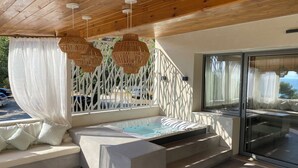 Un área de estar exterior moderna con jacuzzi integrado, techo de madera y ventanas amplias.