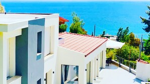 Un edificio moderno con techo rojo, paredes blancas y vista al mar.