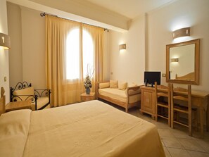 Una habitación de hotel con una cama grande, un escritorio con espejo, televisión y una silla.