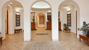 Un pasillo amplio con tres arcos, un mostrador de recepción y una zona de espera.