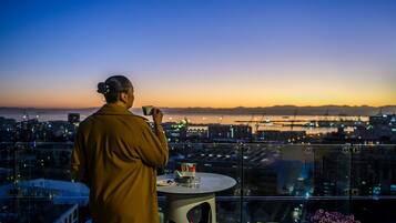 Una persona parada junto a una mesa con vista a la ciudad al anochecer.