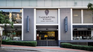En modern byggnad med en skylt som visar texten: ”The Capital Mirage Hotels | Apartments”.