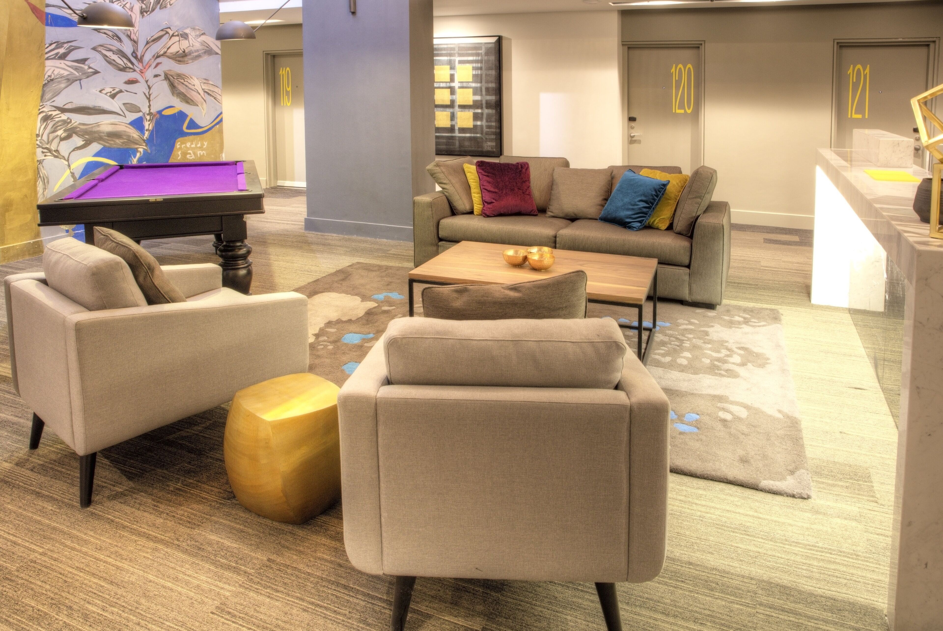 A modern lobby with a pool table, comfortable seating, and a reception desk.