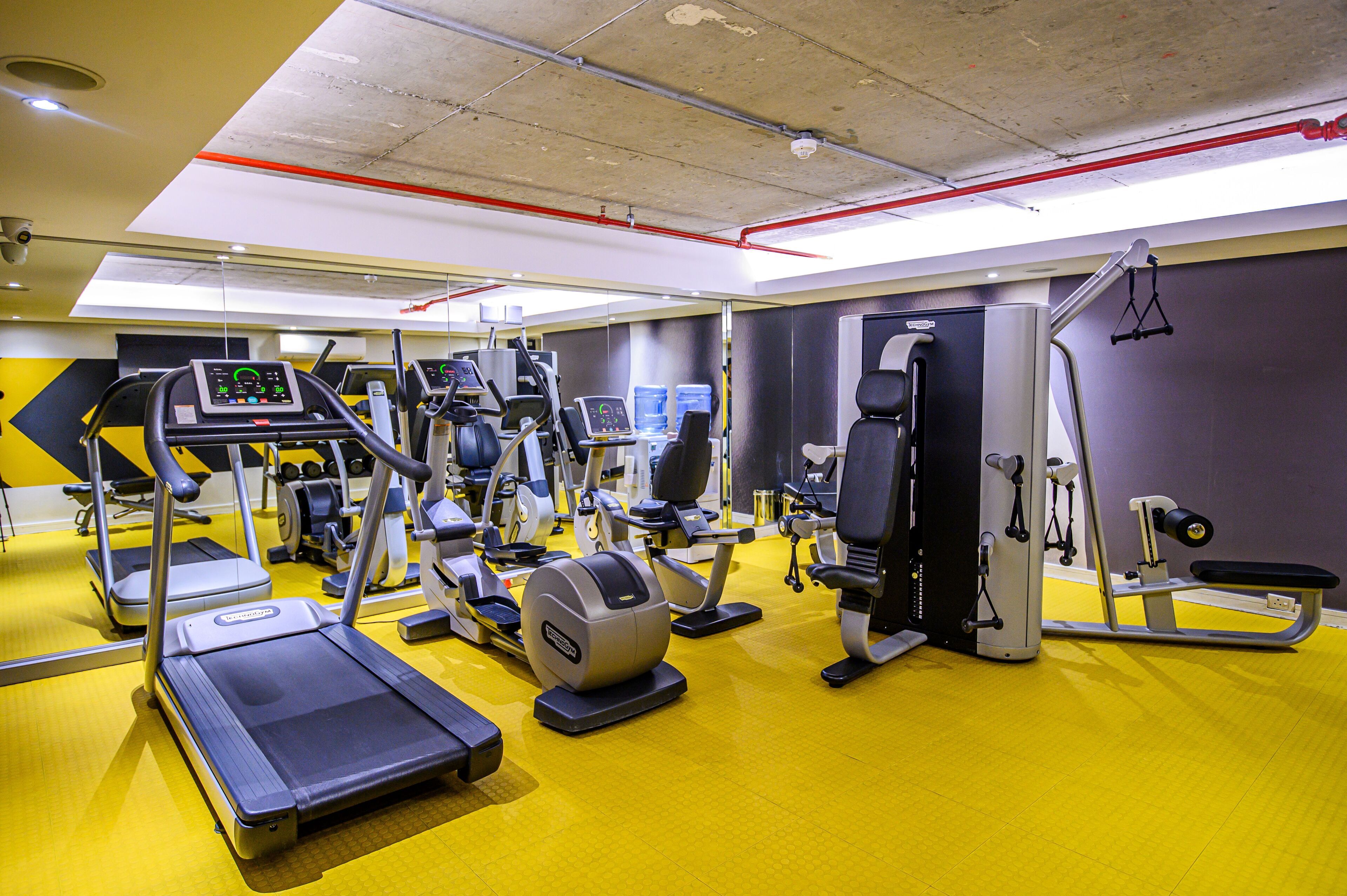 Uma academia com diversos equipamentos de exercícios, incluindo esteiras, elípticos e aparelhos de musculação.