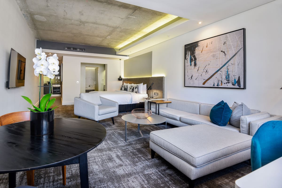 A modern living room with a sofa, a coffee table, and a dining table. There is a plant on the dining table.