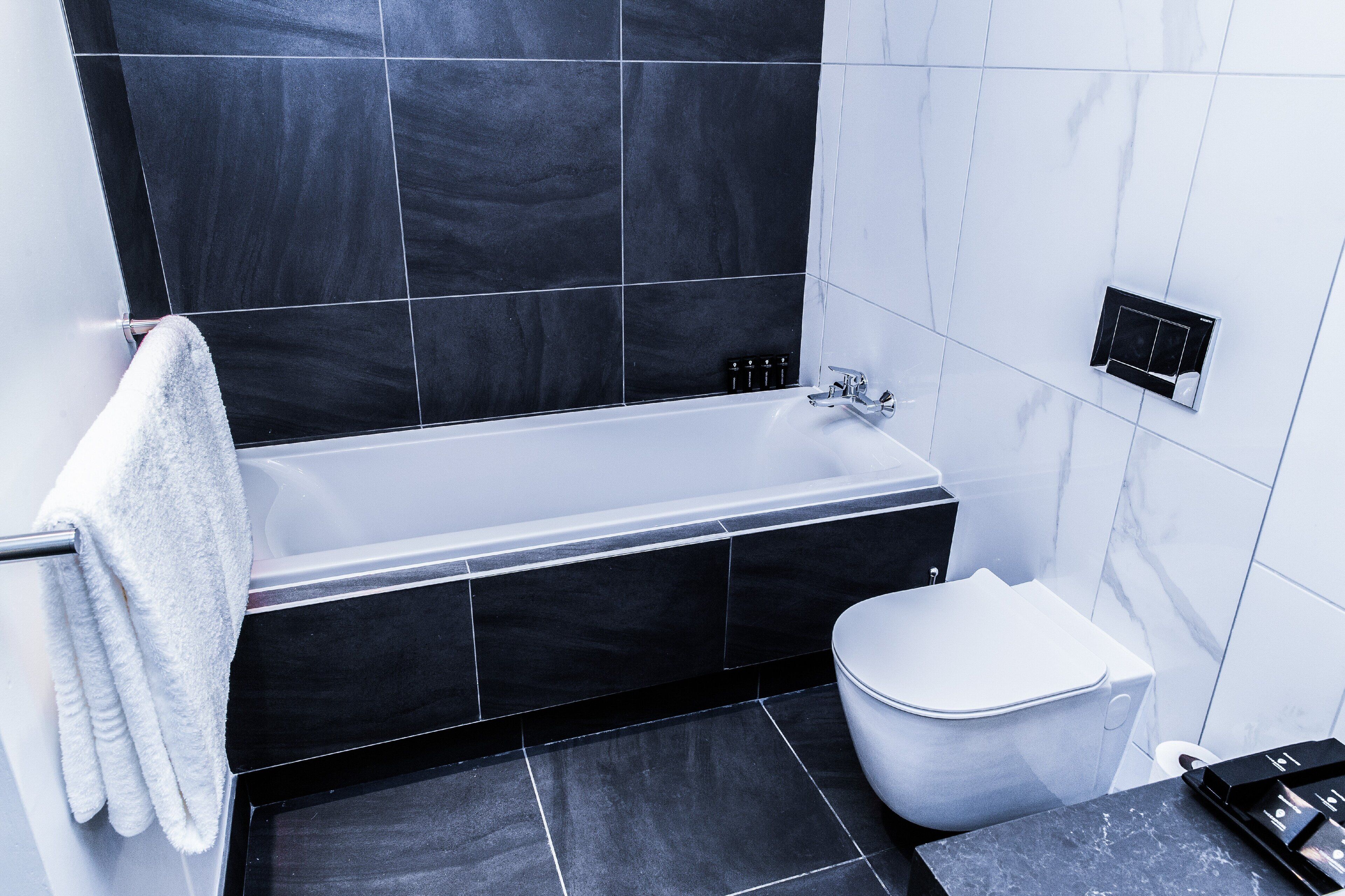 A modern bathroom with a bathtub, toilet, and a towel rack.