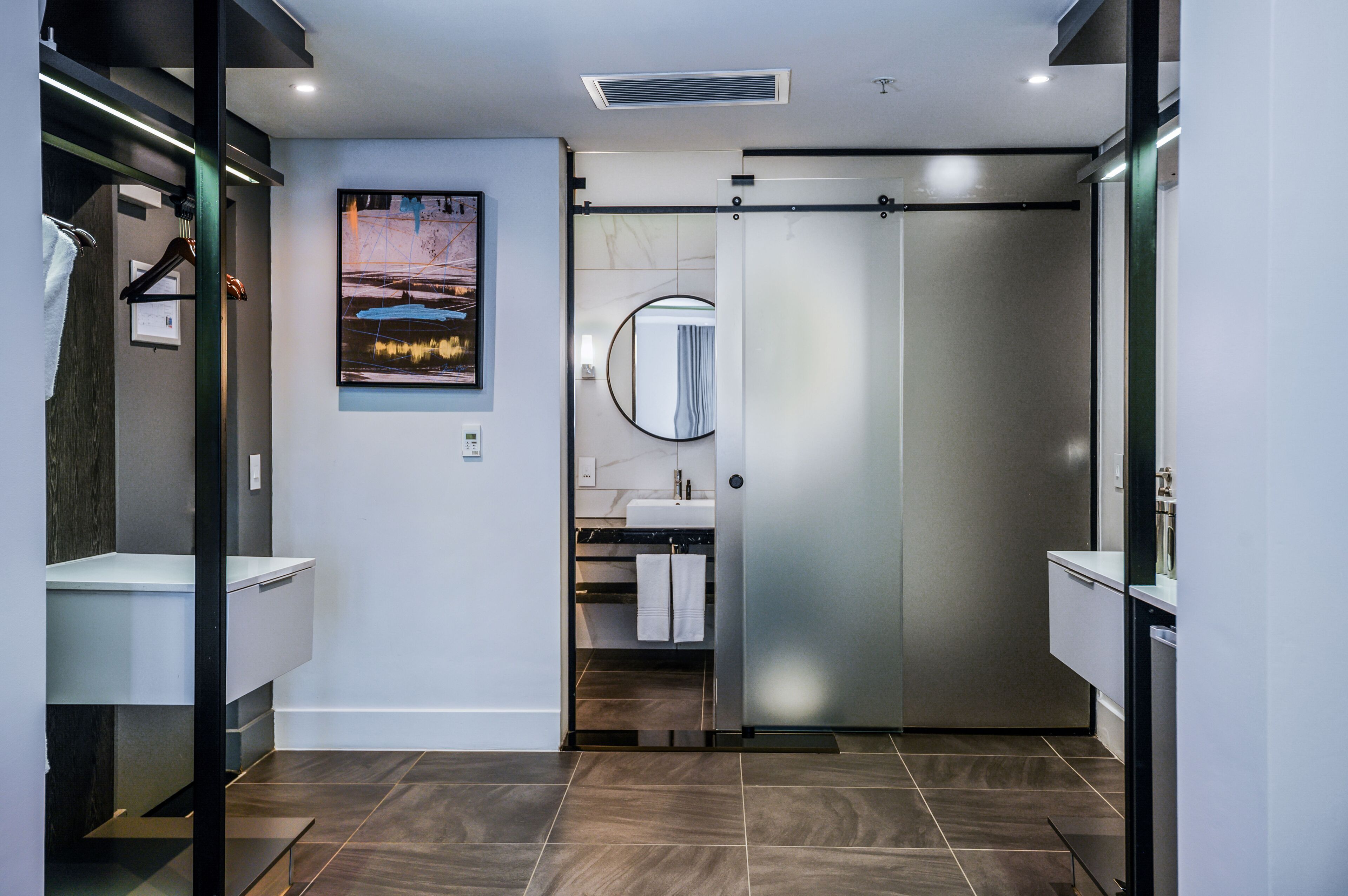 A modern bathroom with a sliding door, a large mirror, and a vanity with a sink.