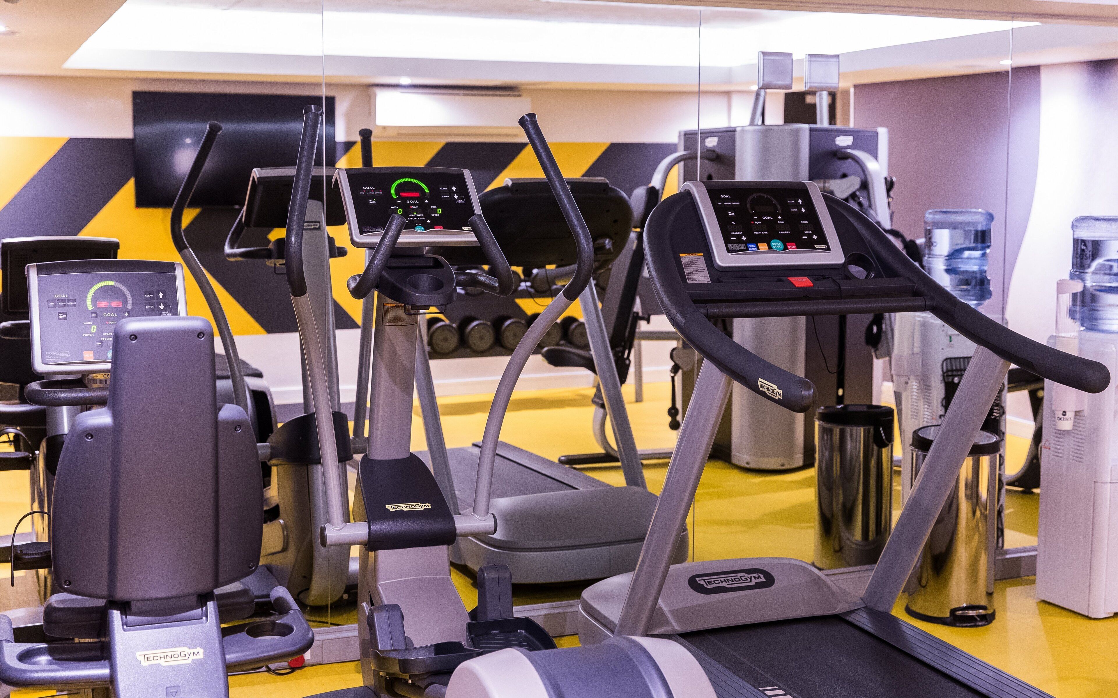 Une salle de sport équipée de tapis de course, de vélos elliptiques et d’appareils de musculation.