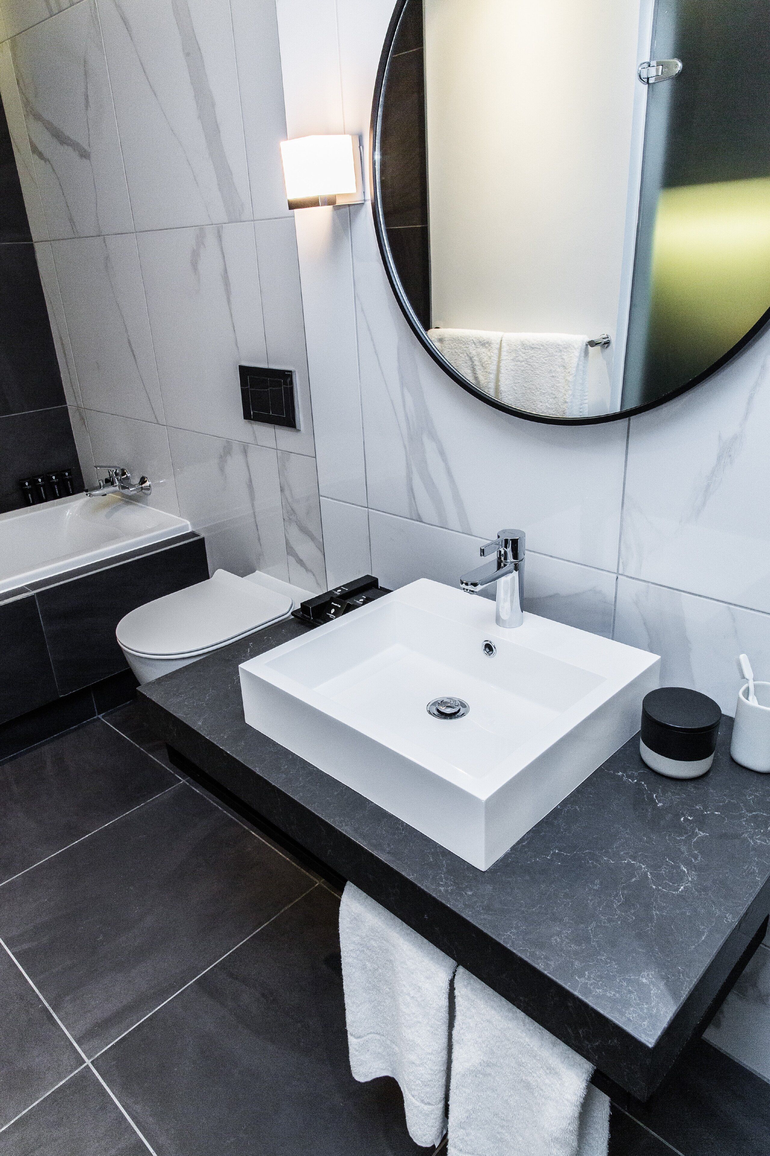A modern bathroom with a white sink, a bathtub, and a toilet.