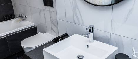 A modern bathroom with a white sink, a bathtub, and a toilet.