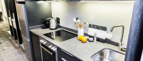 Una cocina moderna con electrodomésticos de acero inoxidable, un lavamanos doble y una cafetera.