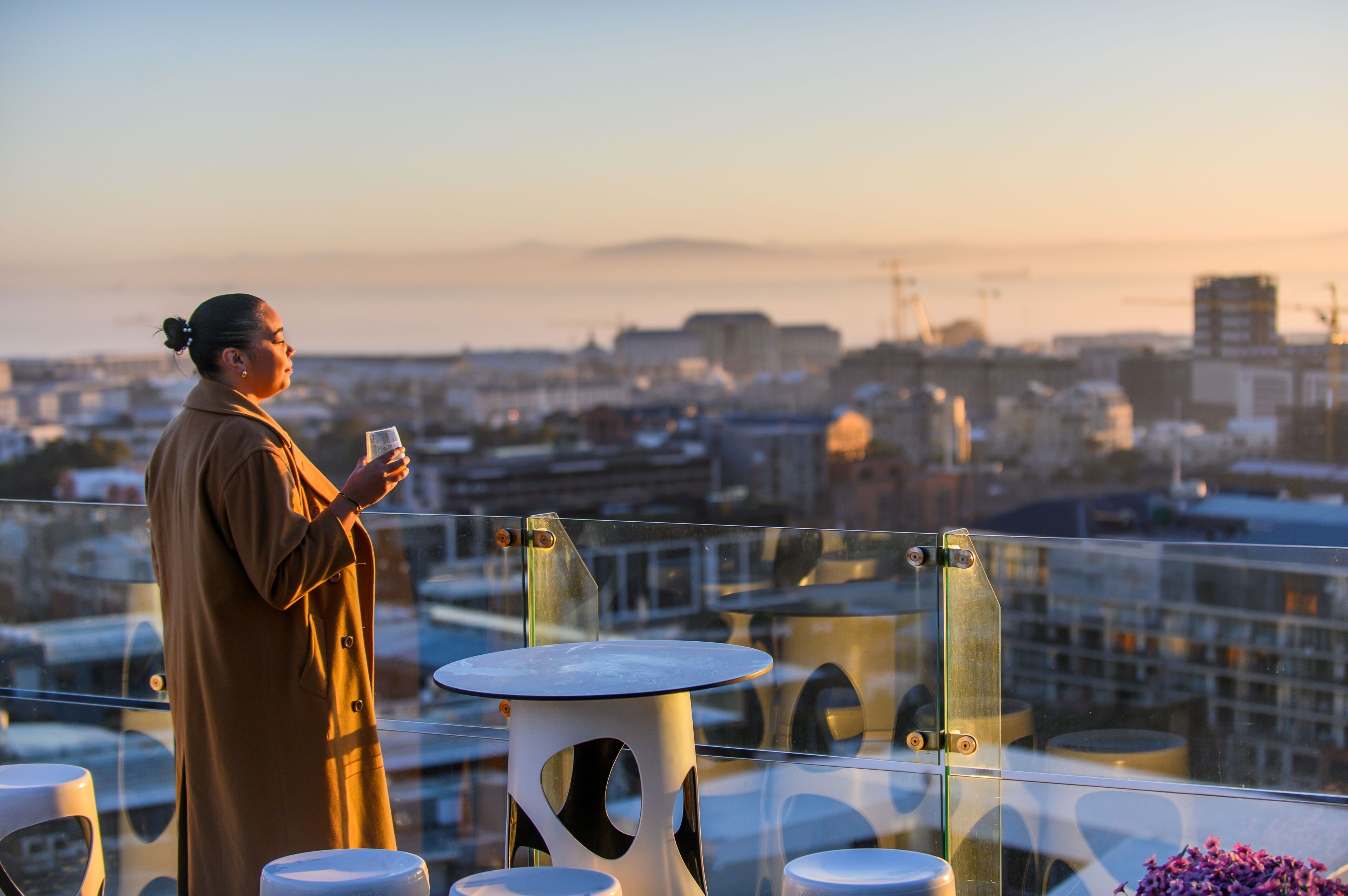 A person standing on a balcony with a cityscape view in the background.