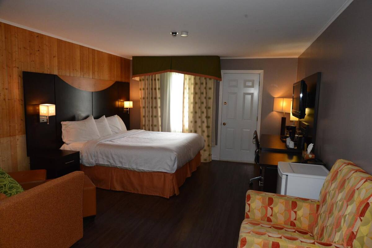 Ein Hotelzimmer mit Bett, Fernseher, Schreibtisch und Stuhl.