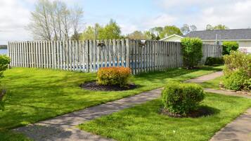 A residential property with a wooden fence, a lawn, and a pathway.