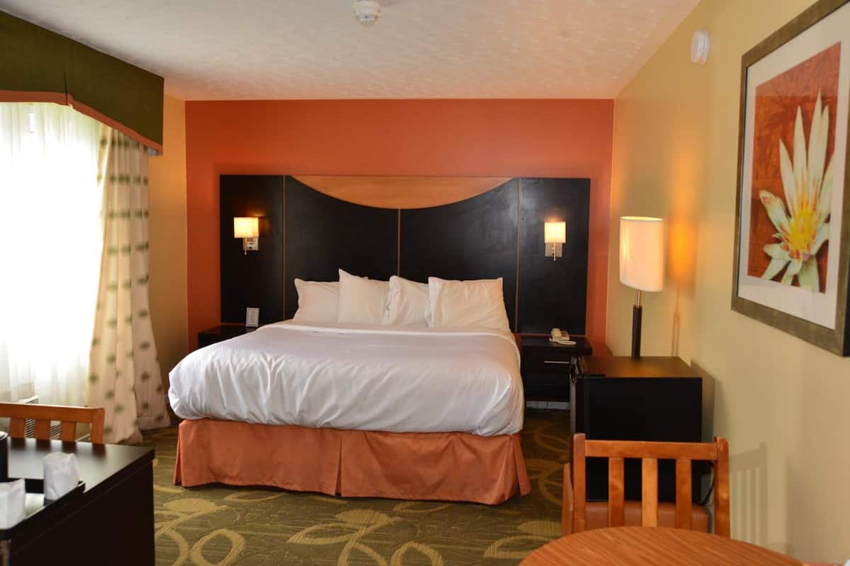 Ein Hotelzimmer mit einem großen Bett, zwei Nachttischen, einem Schreibtisch und einem Stuhl.