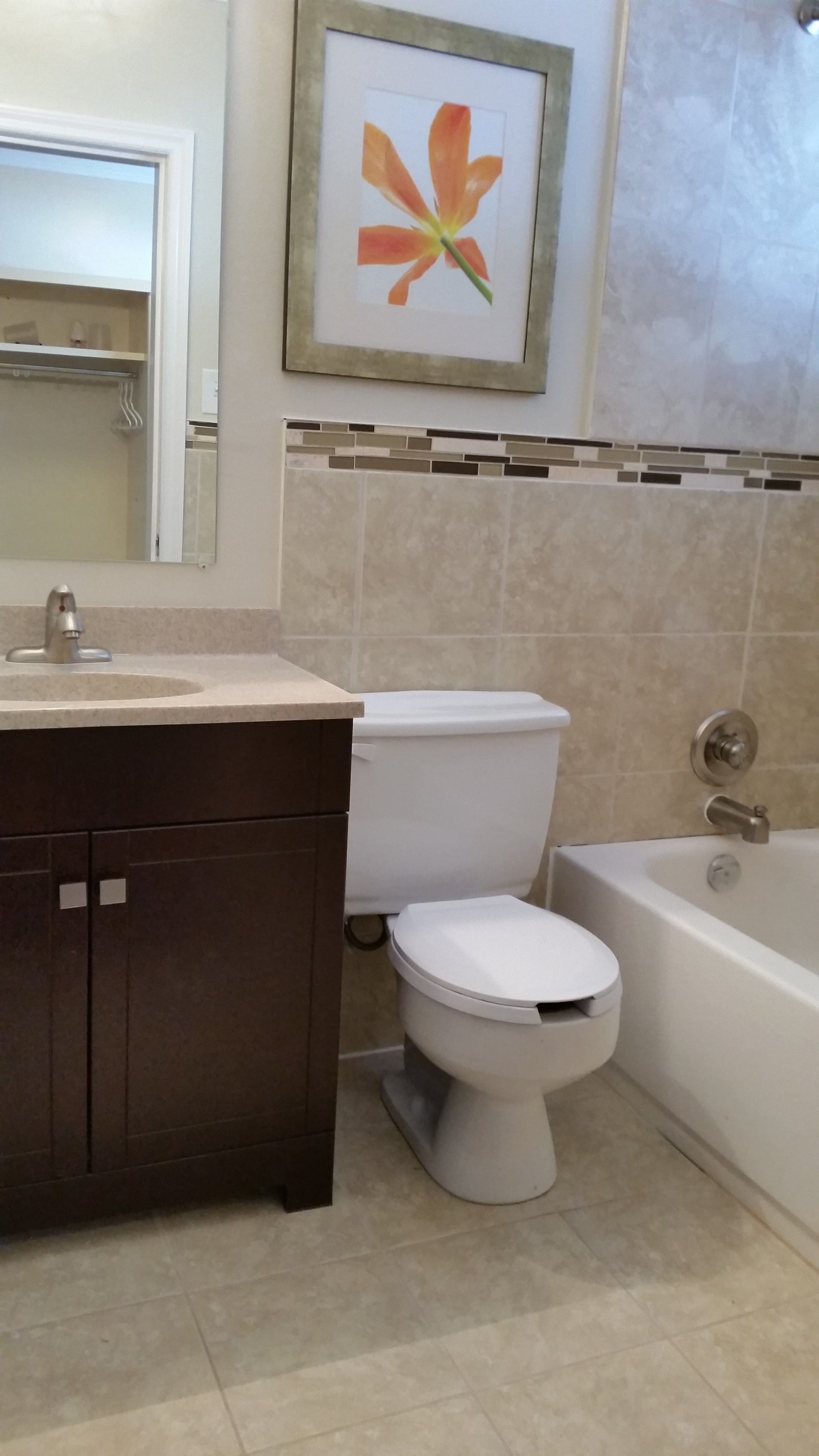 A bathroom with a white toilet, a bathtub, and a sink with a mirror.