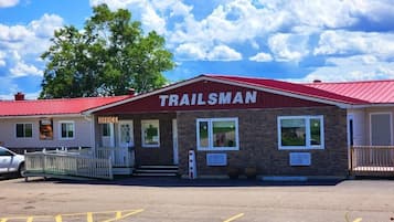 Welcome to Trailsman Office, a building with a brick facade and a red roof, surrounded by a white fence and a parking lot.