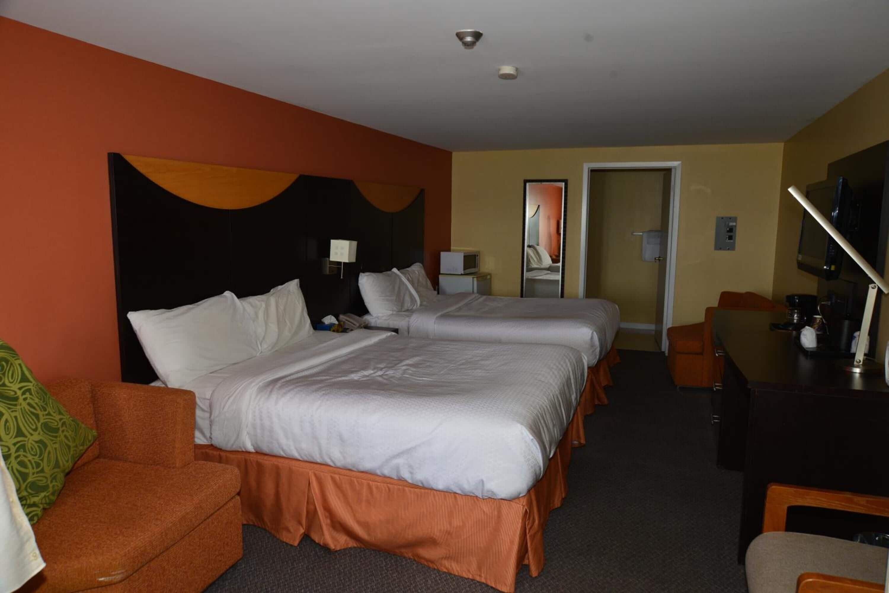 Habitación de hotel con dos camas, un escritorio, una silla y un televisor.