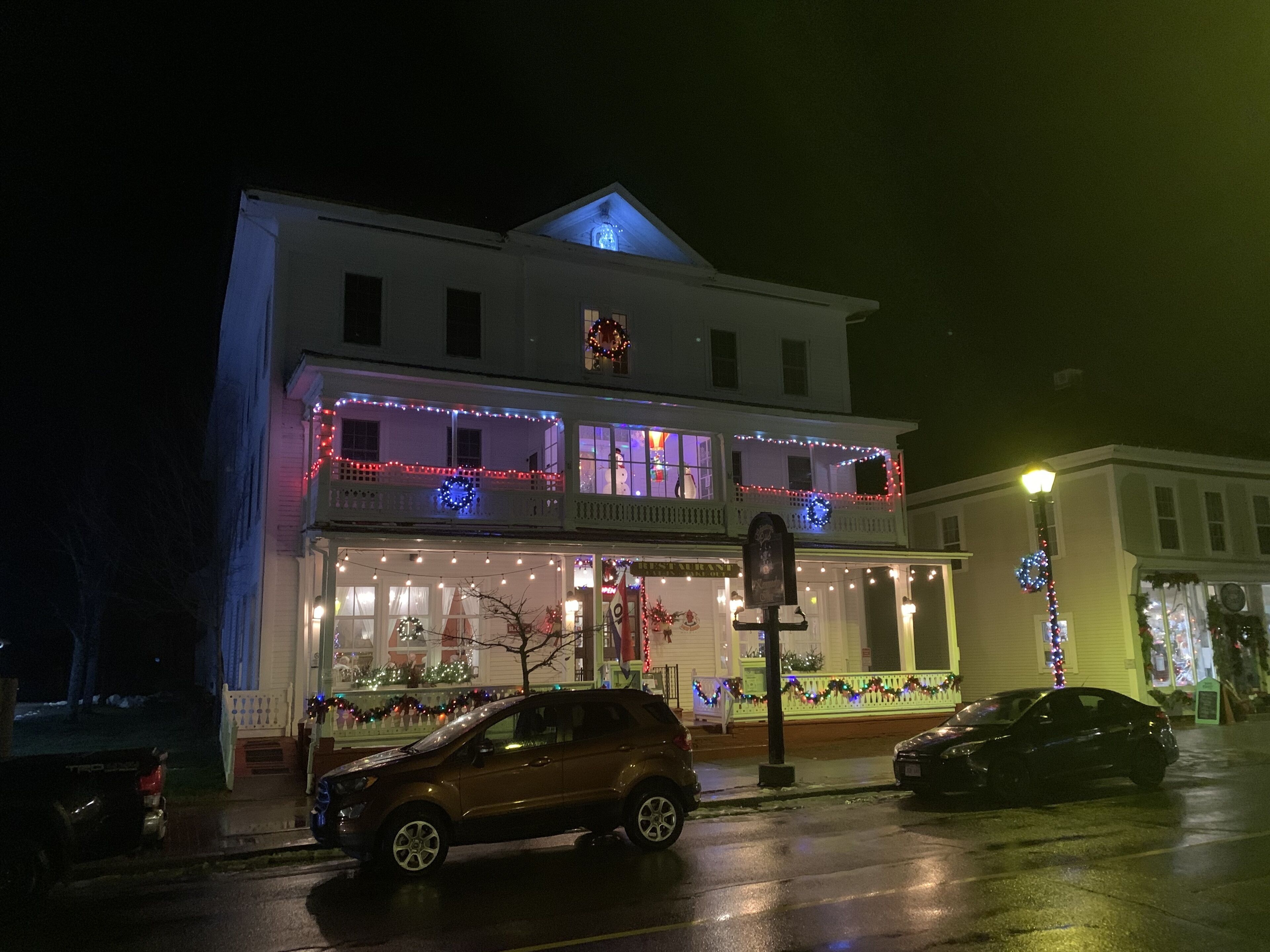 A two-story building with a balcony, decorated with holiday lights and wreaths.