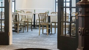 A hotel lobby with wooden chairs, a table, and a sign indicating it is Kennedy's Hotel built in 1881. - Kennedy House (St. Andrews)