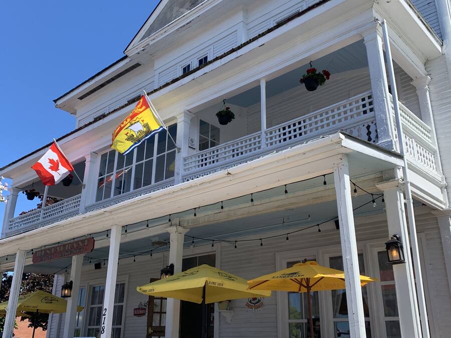 A two-story building with a balcony, a Canadian flag, and a sign for a restaurant.