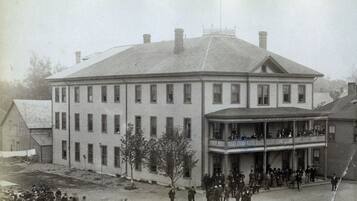 A large, two-story building with a balcony on the ground floor.
