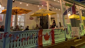 A building with a covered porch, outdoor seating, and a Canadian flag. - Kennedy House (St. Andrews)