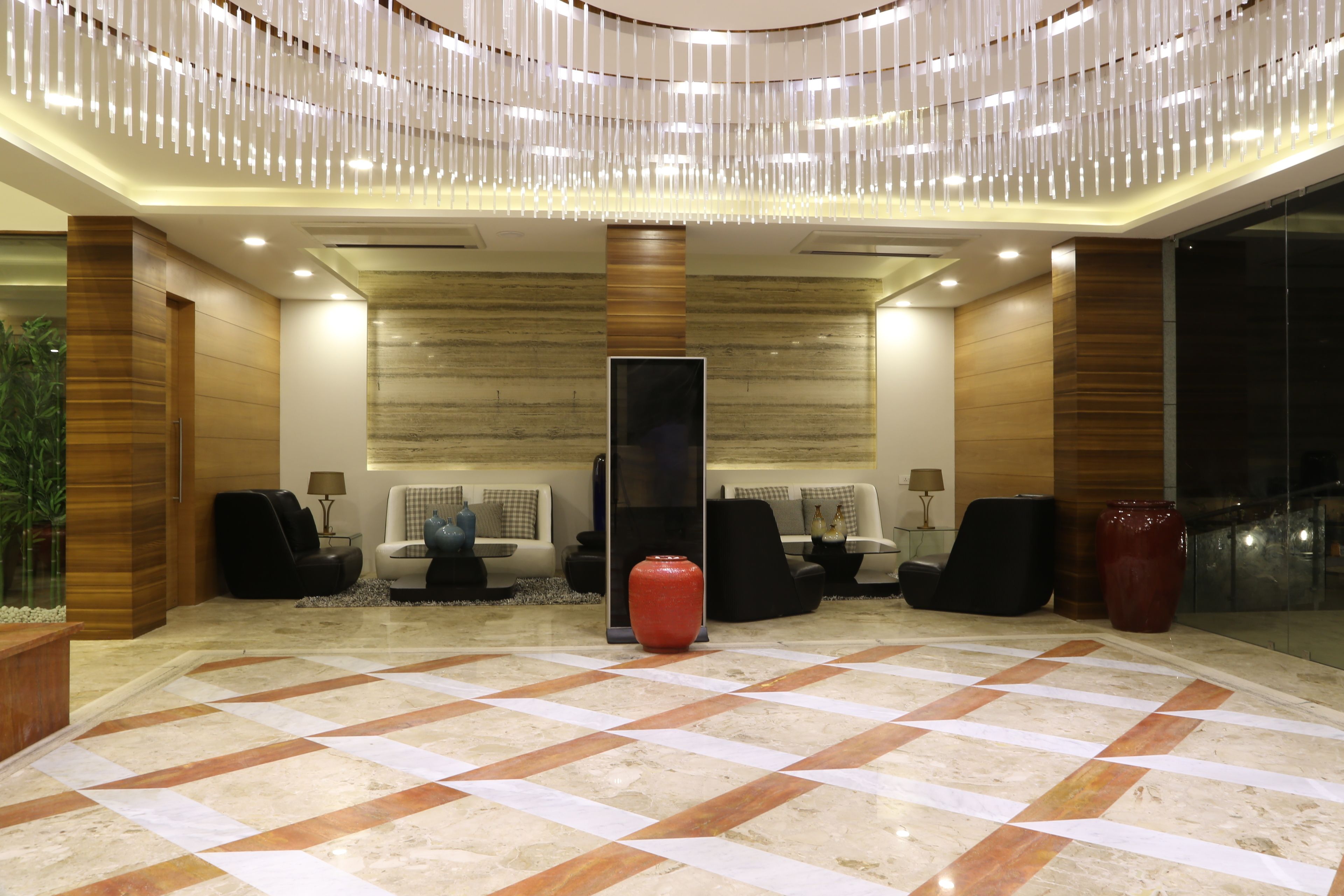 A lobby with a checkered floor, seating area, and a large red vase.
