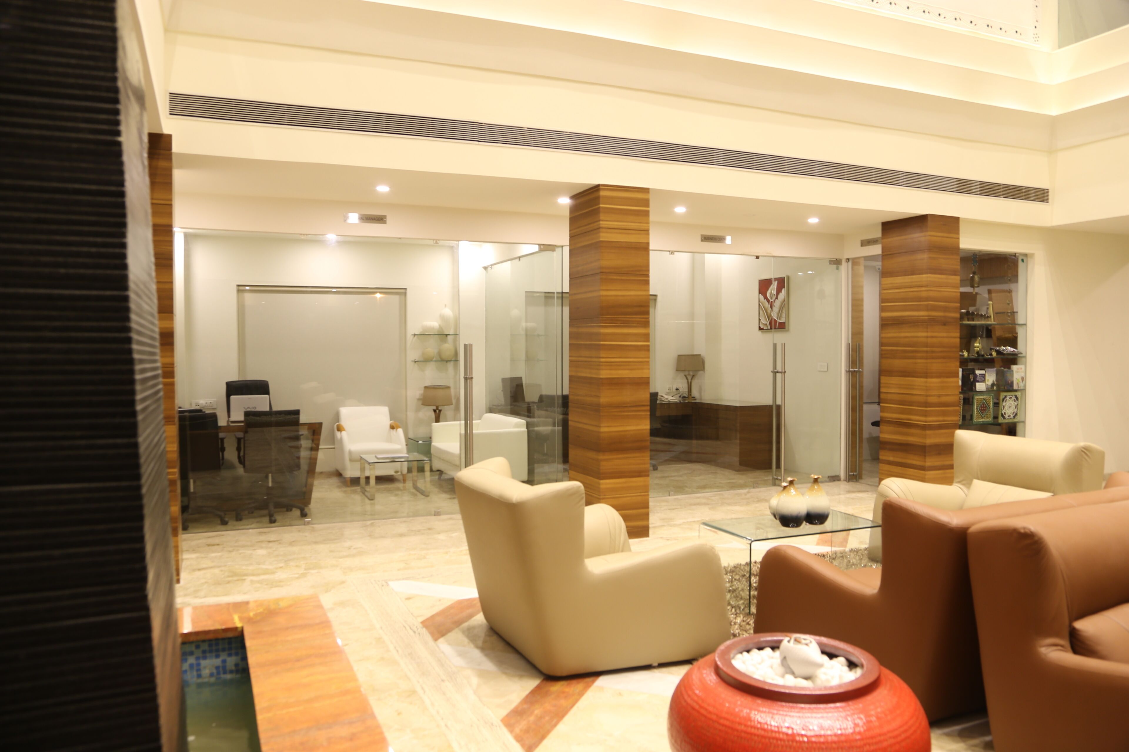 A modern lobby with a reception desk, seating area, and a glass partition.