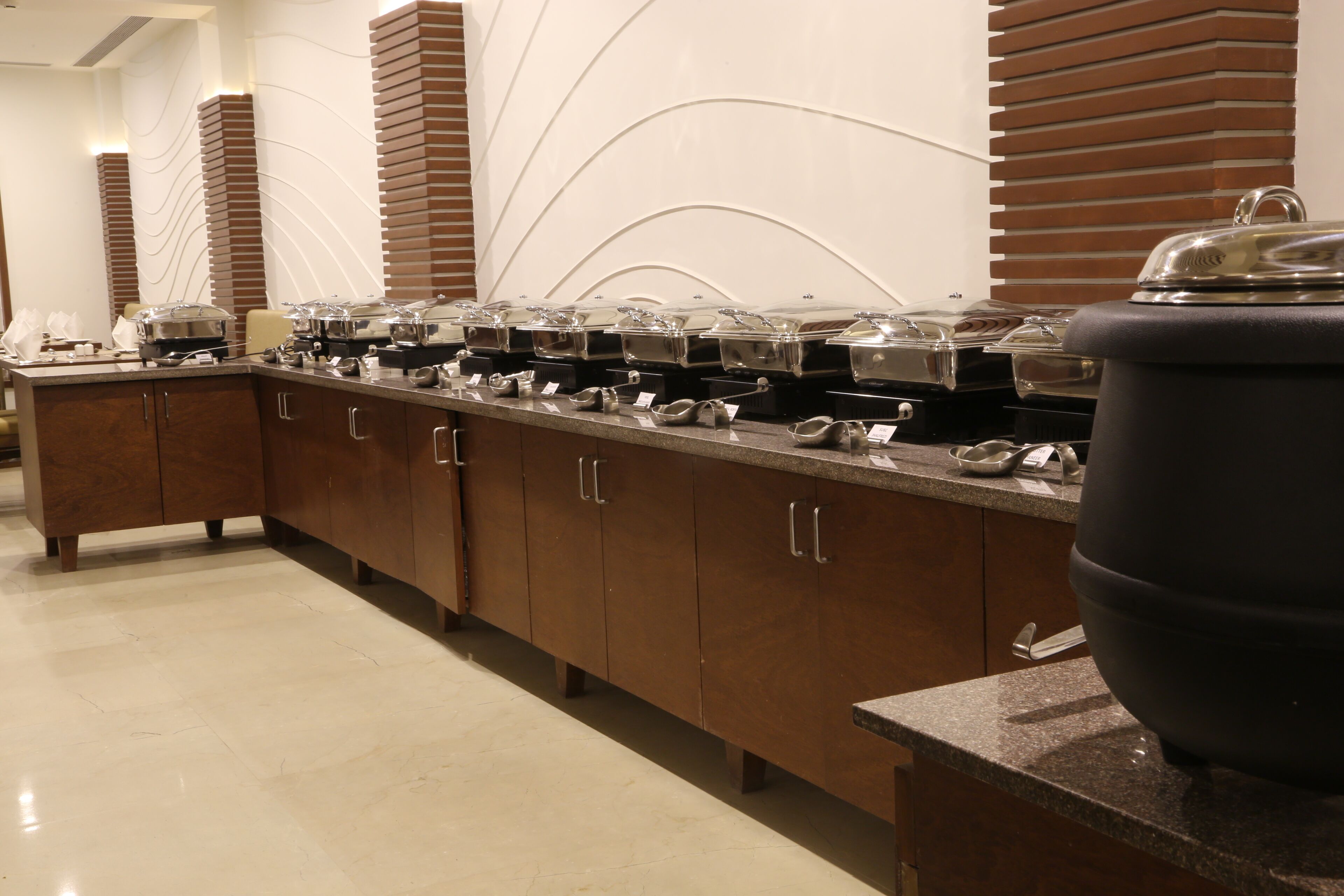 A buffet setup with multiple serving stations, each with a covered food container.