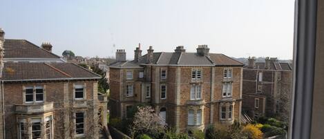 A residential area with brick houses, a clear sky, and parked cars.