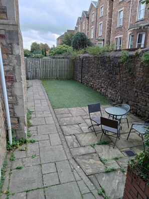 Enjoy a patio area surrounded by a stone wall and a wooden fence, adjacent to a charming brick building.