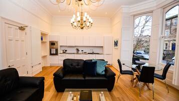 Un salon moderne avec un canapé en cuir noir, une table basse en verre et un coin repas comprenant une table en verre et des chaises noires.