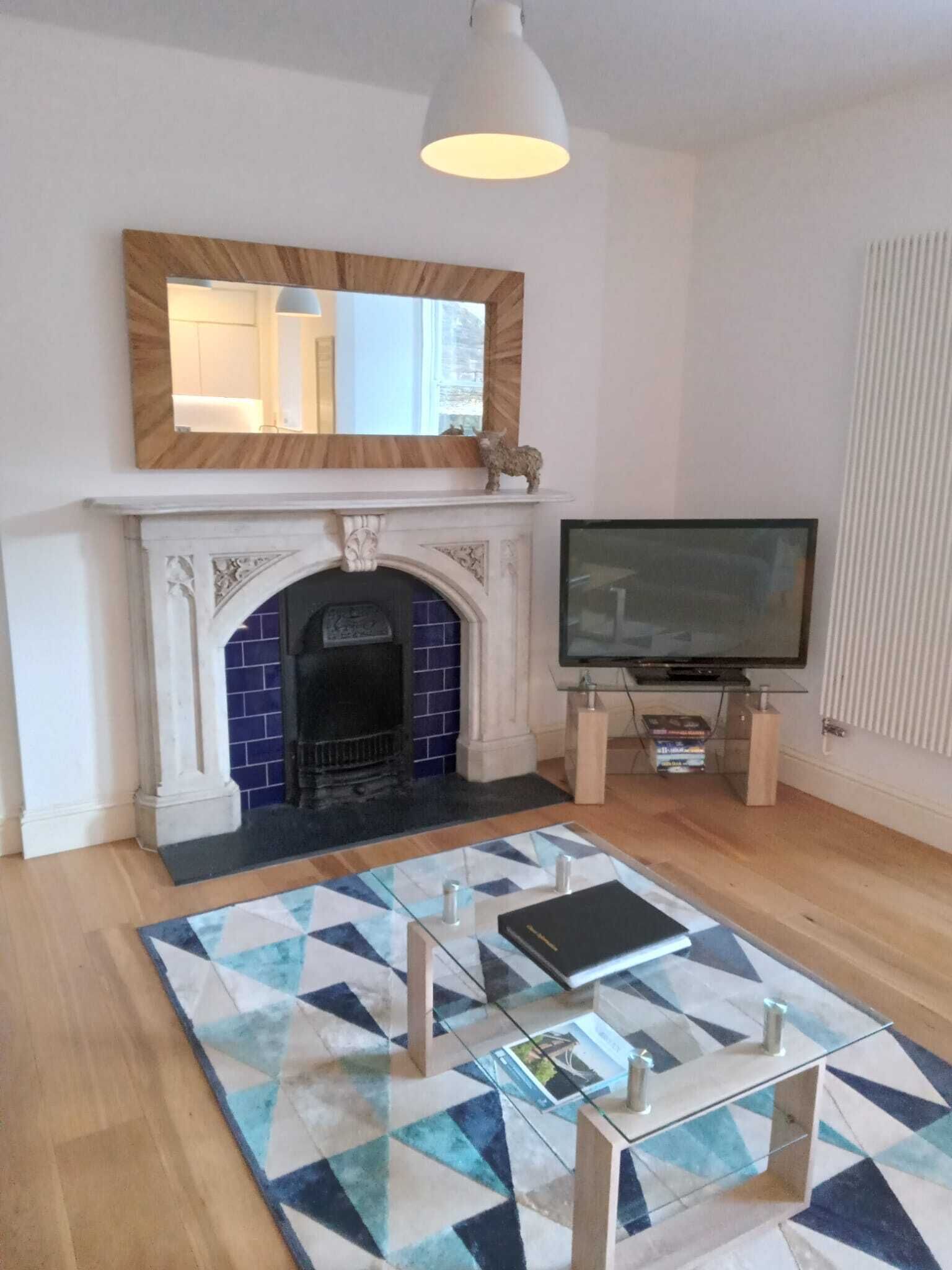 A living room with a fireplace, a television, and a patterned rug.