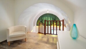 A room with a white sofa, a blue vase, and a wooden gate leading to a balcony with a green curtain. - B&B La Casa nel Giardino (Piano di Sorrento)