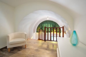 A room with a white sofa, a blue vase, and a wooden gate leading to a balcony with a green curtain. - B&B La Casa nel Giardino (Piano di Sorrento)