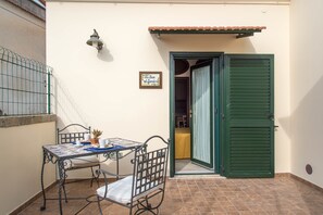 A small outdoor patio with a table and chairs, a green door, and a tiled floor. - B&B La Casa nel Giardino (Piano di Sorrento)