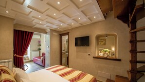 A hotel room with a bed, a TV, a mirror, a wooden staircase, and a red curtain. - B&B La Casa nel Giardino (Piano di Sorrento)