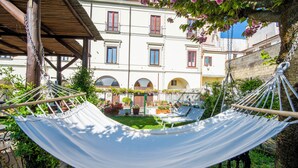 A hammock in a courtyard with a building in the background. - B&B La Casa nel Giardino (Piano di Sorrento)