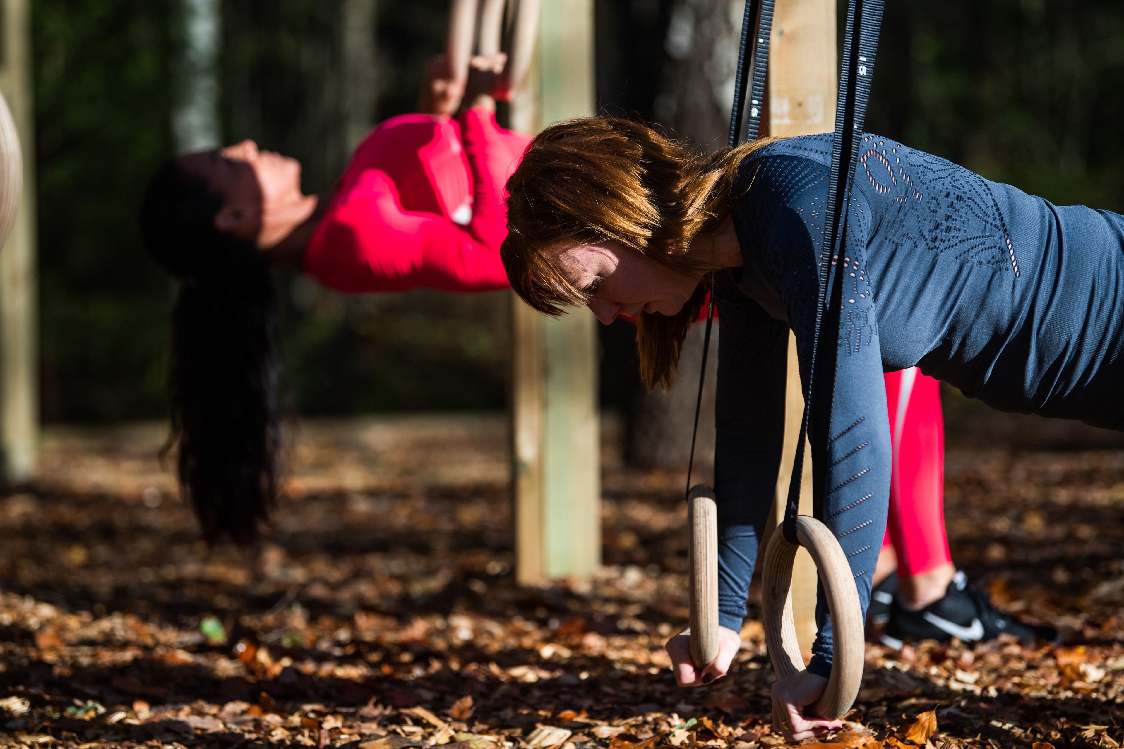 Two people doing a workout with exercise equipment in an outdoor setting.