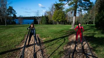 Two people cross-country skiing on a trail with a lake and trees in the background.