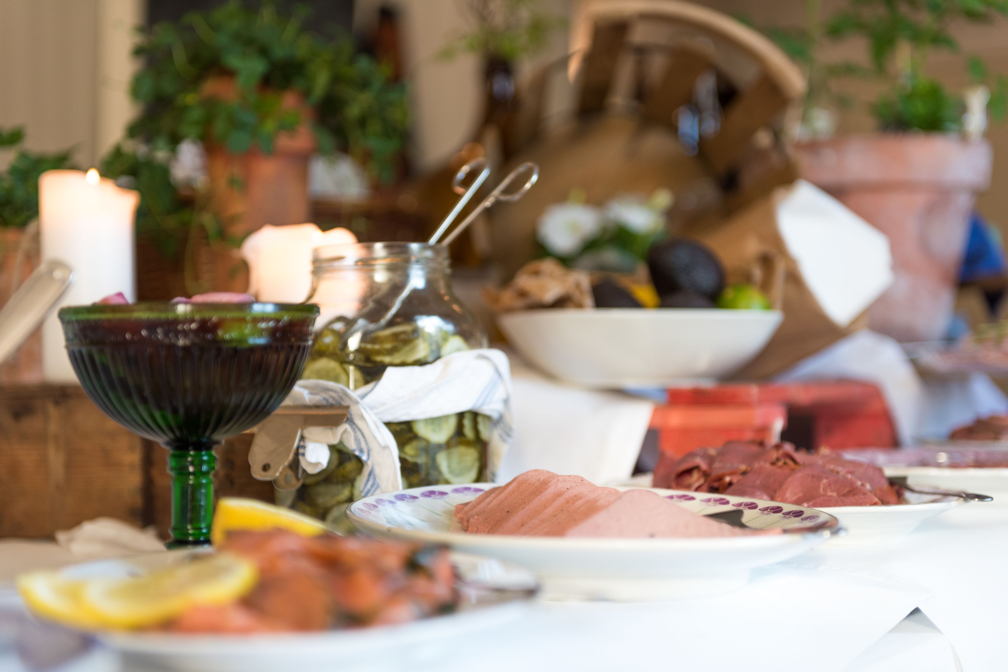Una mesa con diferentes alimentos, una vela y un tazón de vidrio verde.