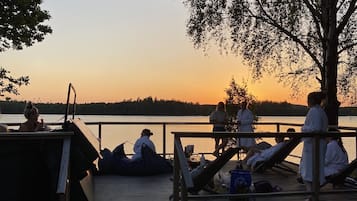 En träbrygga med trappsteg som leder upp till en plattform där folk sitter och kopplar av.