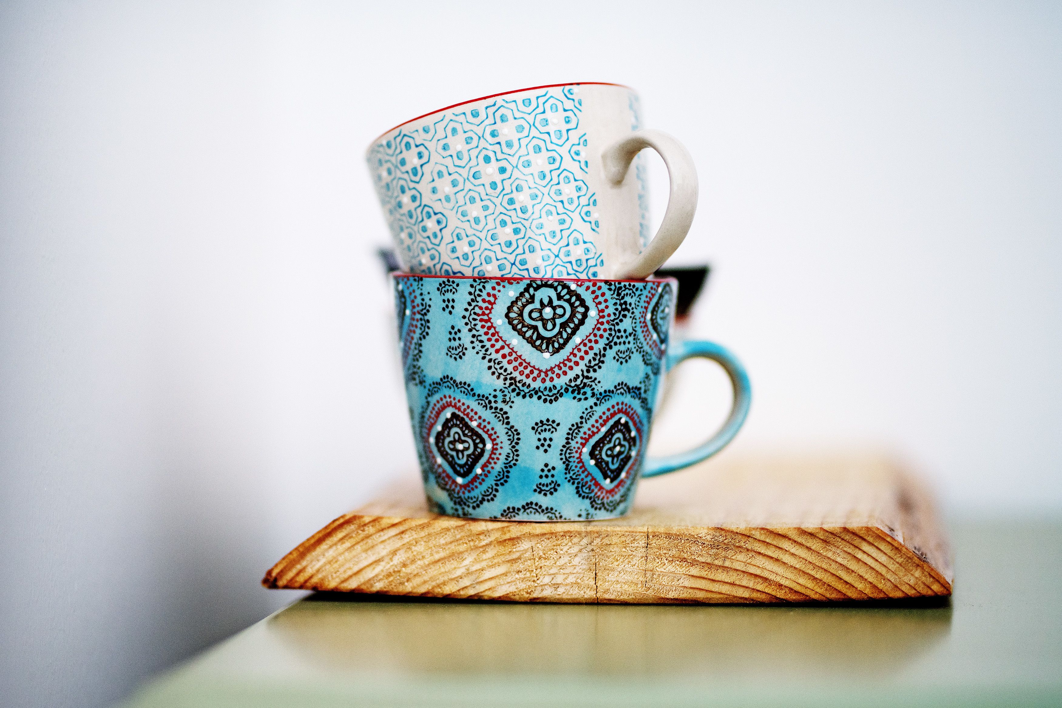 Deux tasses superposées, ornées de motifs complexes, posées sur une surface en bois.