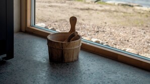 A wooden bucket on a window sill, a view of a lake, and a building exterior. - Två Skyttlar (Orby)