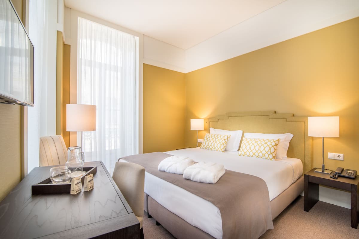 Een hotelkamer met een bed, nachtkastjes, een bureau en een stoel.
