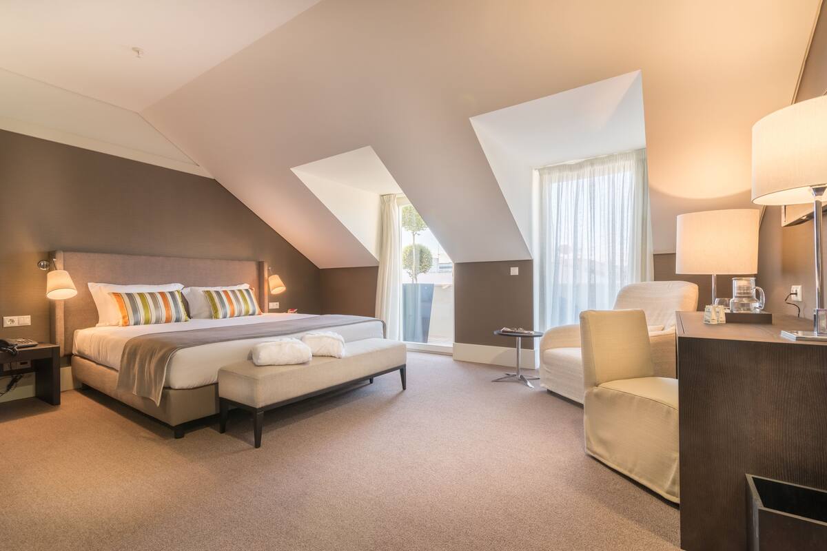 Een moderne hotelkamer met een groot bed, een bureau, een stoel en uitzicht op de omgeving.