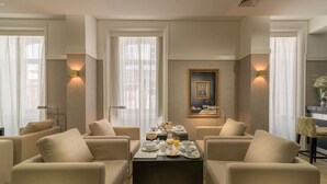 Un coin repas avec une table mise pour le petit-déjeuner, entouré de canapés, et un portrait encadré accroché au mur.